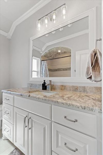 Full bathroom with toilet, vanity, vaulted ceiling, tiled shower, and crown molding