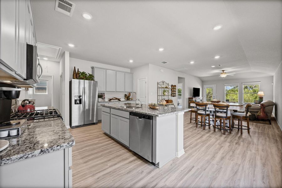 An open floor plan seamlessly connects the stone-countertop kitchen to the main living area.