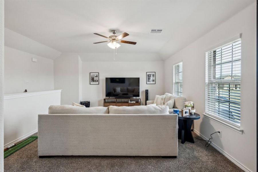 Carpeted living room featuring ceiling fan and lofted ceiling