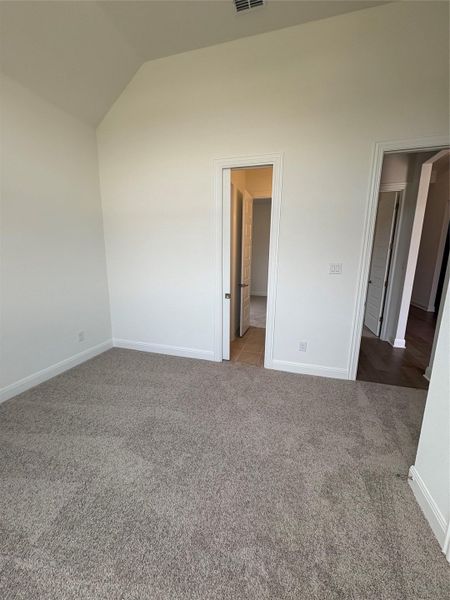 Unfurnished room with carpet flooring, vaulted ceiling, and baseboards Unfurnished room with carpet flooring, vaulted ceiling, and baseboards