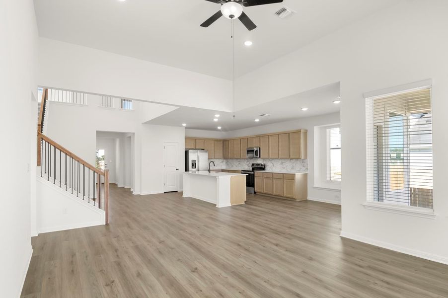 Kitchen featuring open floor plan, appliances with stainless steel finishes, a kitchen island with sink, backsplash, and recessed lighting