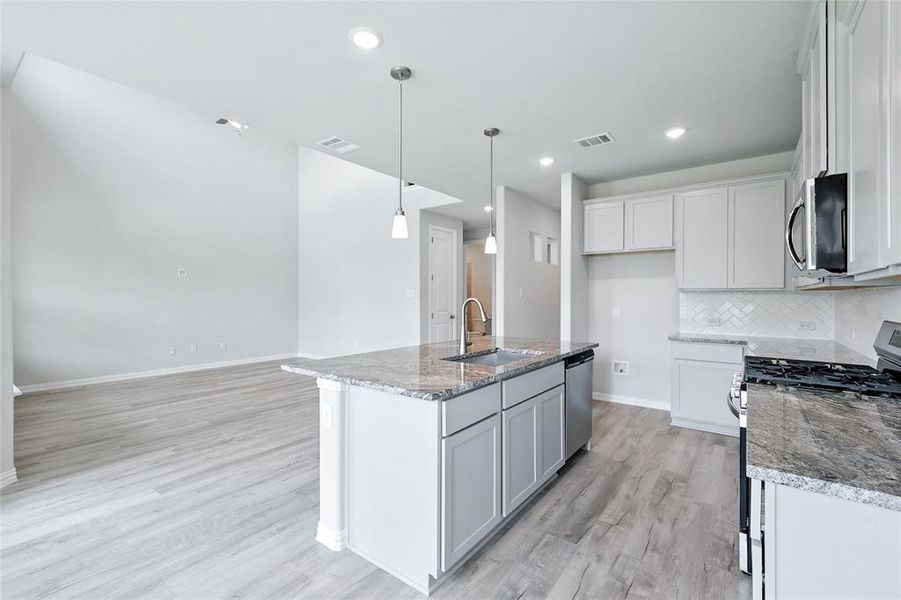 Kitchen with appliances with stainless steel finishes, light wood finished floors, stone counters, backsplash, and recessed lighting Kitchen with appliances with stainless steel finishes, light wood finished floors, stone counters, backsplash, and recessed lighting