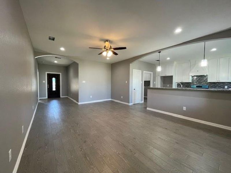 Living room facing front door with arched walkway, wood-style flooring, recessed lighting, a ceiling fan, and baseboards Living room facing front door with arched walkway, wood-style flooring, recessed lighting, a ceiling fan, and baseboards