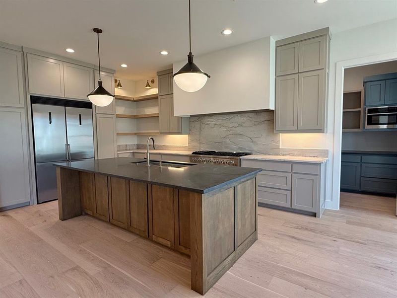 Kitchen. Decorative pendants, custom cabinetry, large vent a hood, built in commercial grades appliances, large serving island.