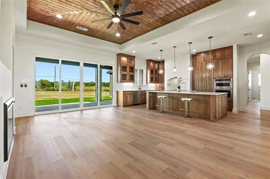 Kitchen with a raised ceiling, wood ceiling, glass insert cabinets, tasteful backsplash, and arched walkways Kitchen with a raised ceiling, wood ceiling, glass insert cabinets, tasteful backsplash, and arched walkways
