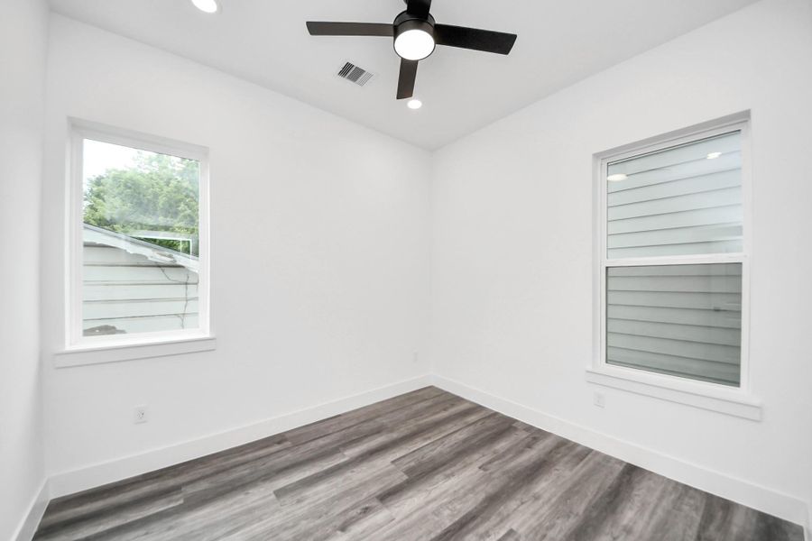 Bright room with modern vinyl flooring, two windows for natural light, and a ceiling fan. Ideal for a cozy bedroom or home office. Bright room with modern vinyl flooring, two windows for natural light, and a ceiling fan. Ideal for a cozy bedroom or home office.