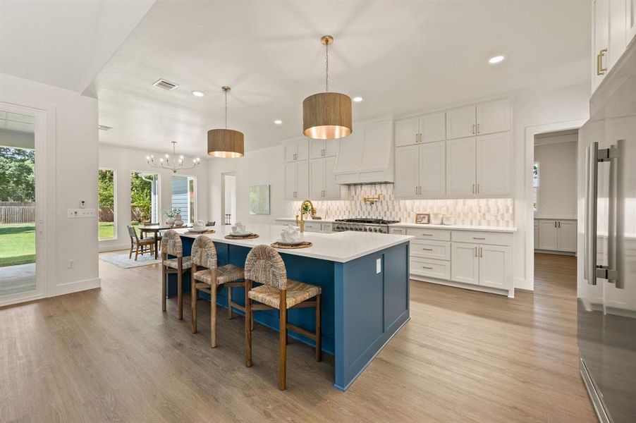 Kitchen with light countertops, high end refrigerator, white cabinets, light wood finished floors, and recessed lighting Kitchen with light countertops, high end refrigerator, white cabinets, light wood finished floors, and recessed lighting