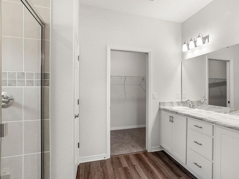 The dual vanity owner`s bath has a tiled shower and a closeted toilet.