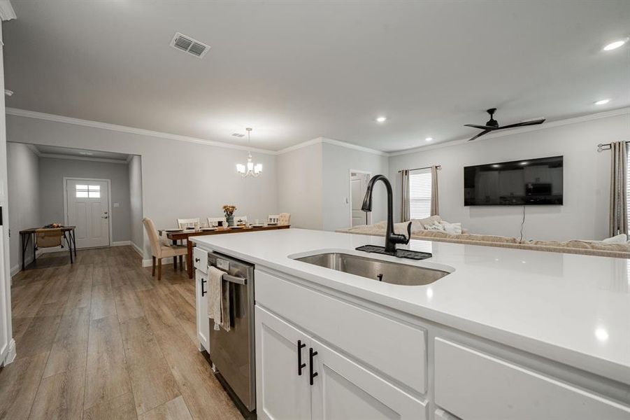 Kitchen with light wood-style flooring, ornamental molding, white cabinetry, healthy amount of natural light, and dishwasher Kitchen with light wood-style flooring, ornamental molding, white cabinetry, healthy amount of natural light, and dishwasher