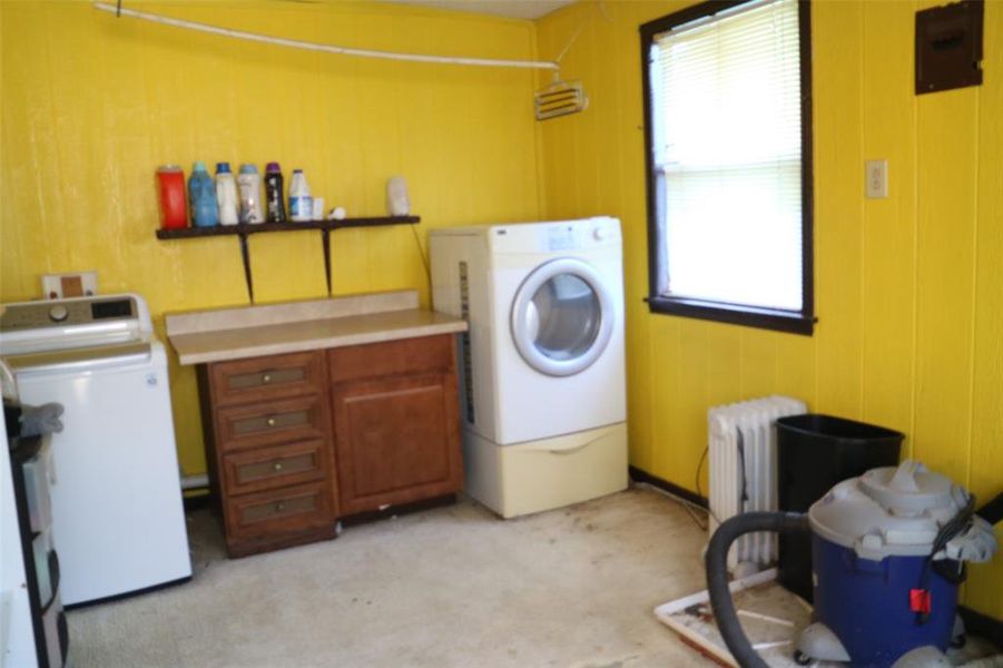Washroom with radiator, independent washer and dryer, and wood walls Washroom with radiator, independent washer and dryer, and wood walls