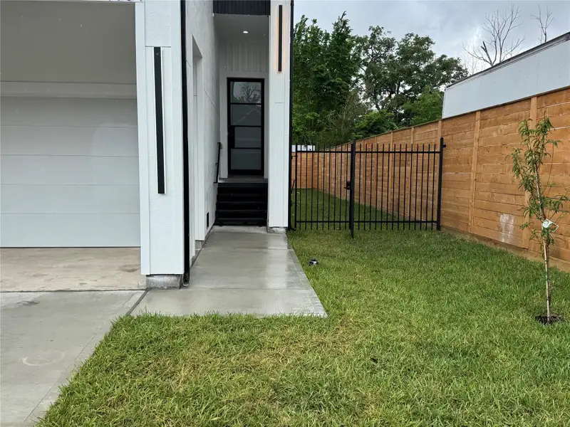 Front entrance features an 8-ft iron door with open green space along the side