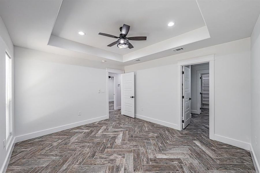 Unfurnished bedroom featuring a tray ceiling, recessed lighting, and ceiling fan Unfurnished bedroom featuring a tray ceiling, recessed lighting, and ceiling fan
