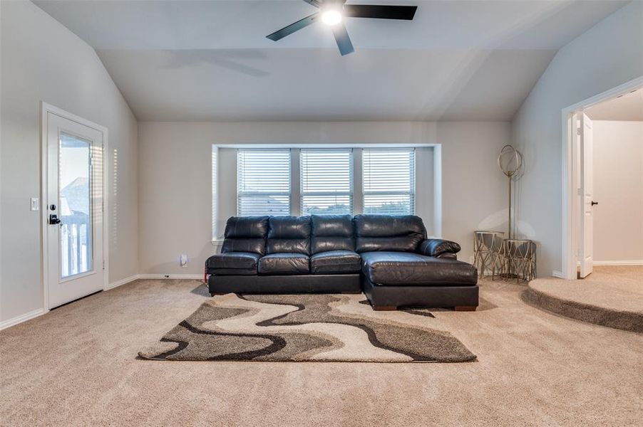Living area with vaulted ceiling, carpet, and ceiling fan Living area with vaulted ceiling, carpet, and ceiling fan