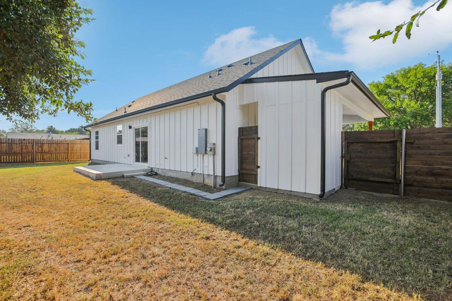 Back of house featuring board and batten siding, a fenced backyard, and a shingled roof