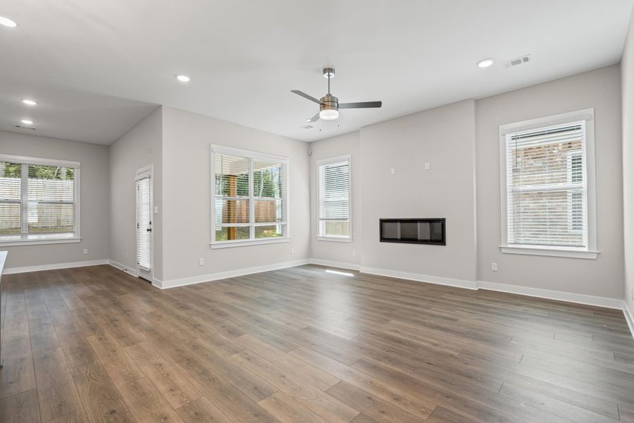 Unfurnished living room featuring a glass covered fireplace, recessed lighting, wood finished floors, and ceiling fan