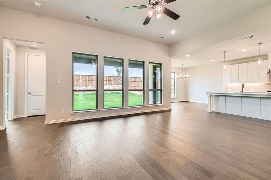 Unfurnished living room with dark hardwood / wood-style flooring and ceiling fan with notable chandelier