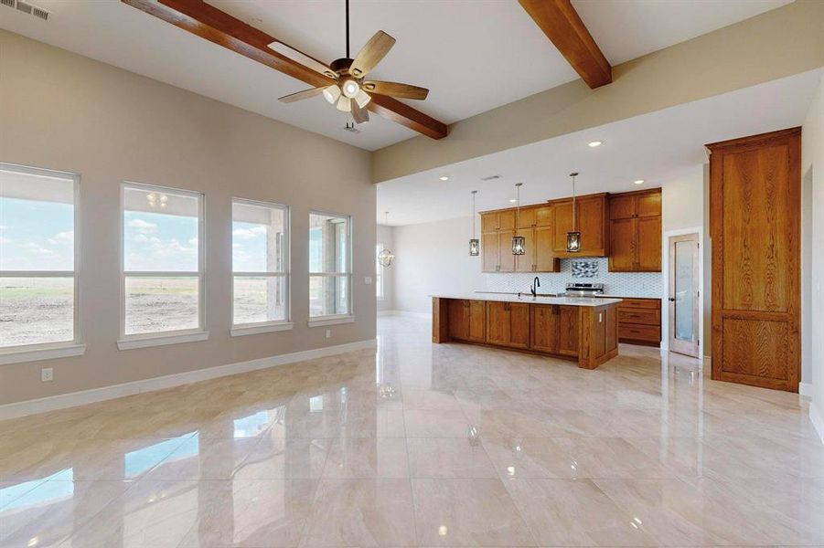 Kitchen featuring beamed ceiling, decorative light fixtures, light tile patterned floors, a kitchen island with sink, and ceiling fan