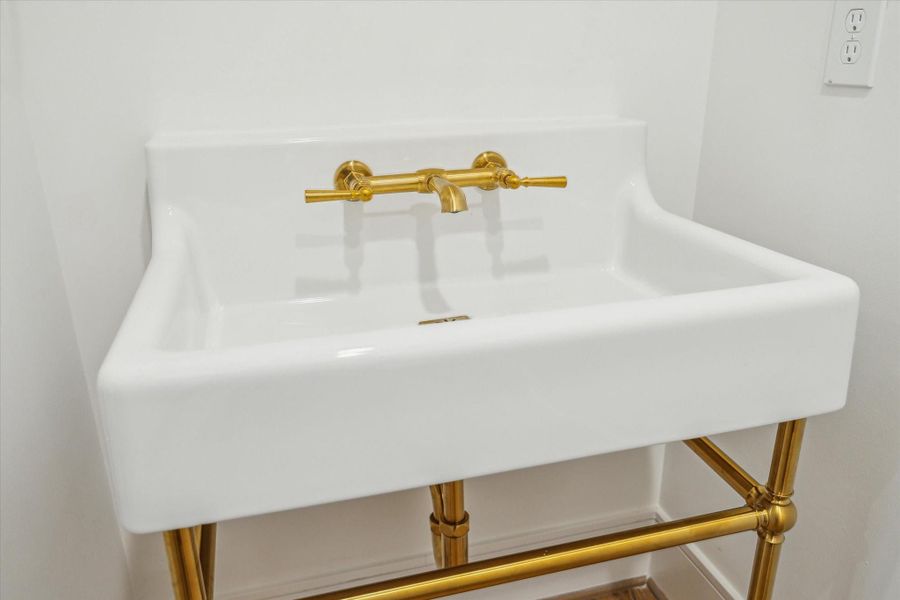 Powder Bath features console sink with brass details.