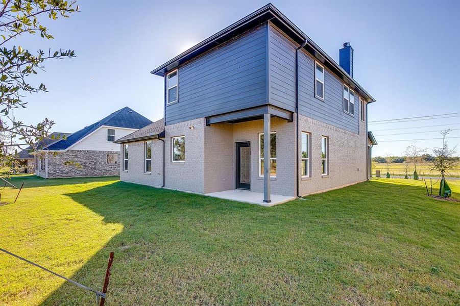 Back of property with a chimney, a patio area, a yard, and brick siding