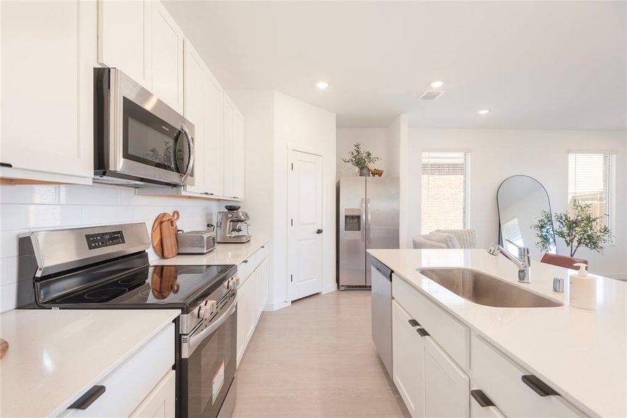 Kitchen with stainless steel appliances, white cabinetry, recessed lighting, light stone countertops, and tasteful backsplash Kitchen with stainless steel appliances, white cabinetry, recessed lighting, light stone countertops, and tasteful backsplash