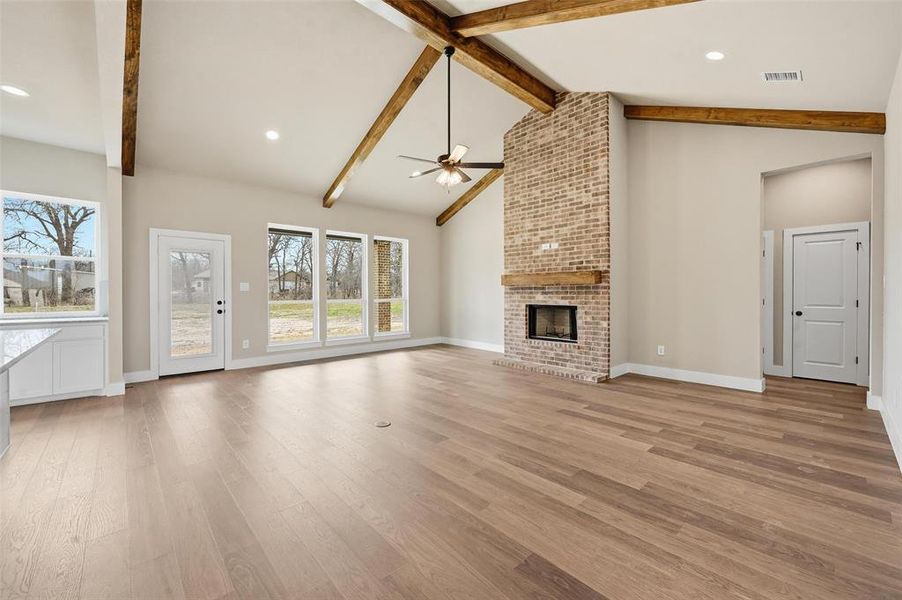 Unfurnished living room featuring a fireplace, light wood-type flooring, a ceiling fan, recessed lighting, and lofted ceiling