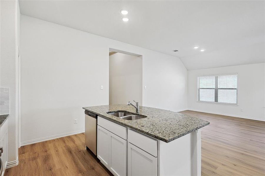 Kitchen with sink, an island with sink, light wood-type flooring, and lofted ceiling