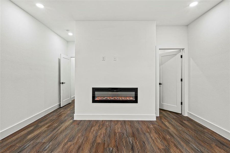 Detailed view of a glass covered fireplace, wood finished floors, and recessed lighting