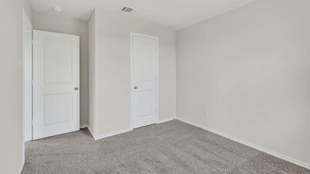 Carpeted interior space featuring light gray walls, white baseboards, and two white paneled doors with brushed nickel hardware Carpeted interior space featuring light gray walls, white baseboards, and two white paneled doors with brushed nickel hardware