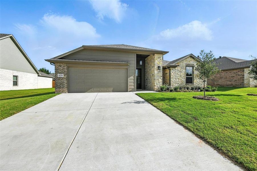 View of front of house with concrete driveway, a front lawn, a garage, and stone siding
