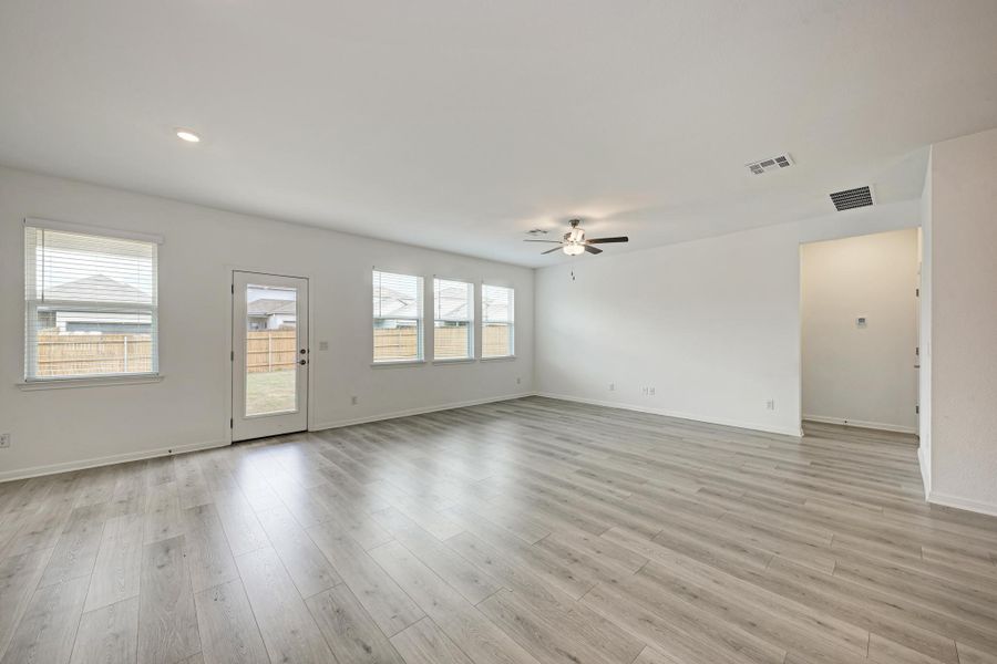 A spacious room offers light wood-look flooring and multiple windows for abundant natural light.
