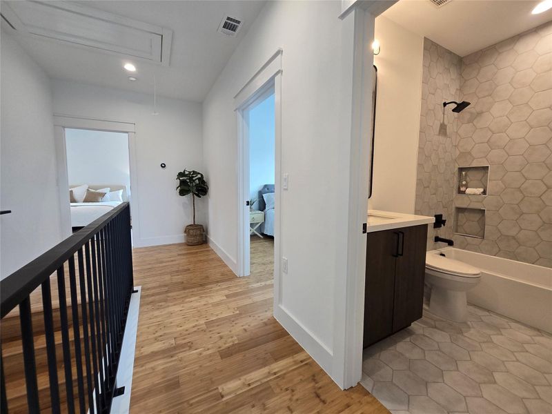 Hallway with attic access, light wood-style flooring, and recessed lighting