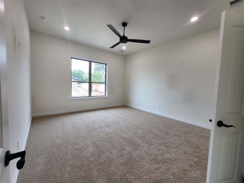 Spacious room featuring neutral carpet flooring, recessed lighting, and a modern ceiling fan