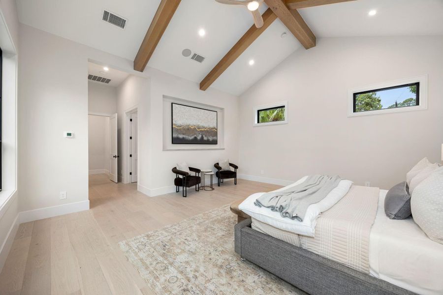 This alternate view of the primary bedroom showcases its generous scale and thoughtful layout, offering multiple areas for relaxation. Clean lines and soft finishes create a calming atmosphere throughout. The highlight is the vaulted ceiling with exposed beams, drawing the eye upward and enhancing the sense of space, while maintaining a warm and inviting feel perfect for everyday living.