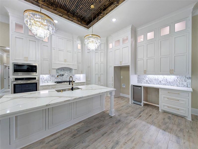 Kitchen featuring tasteful backsplash, light stone countertops, stainless steel appliances, glass insert cabinets, and recessed lighting
