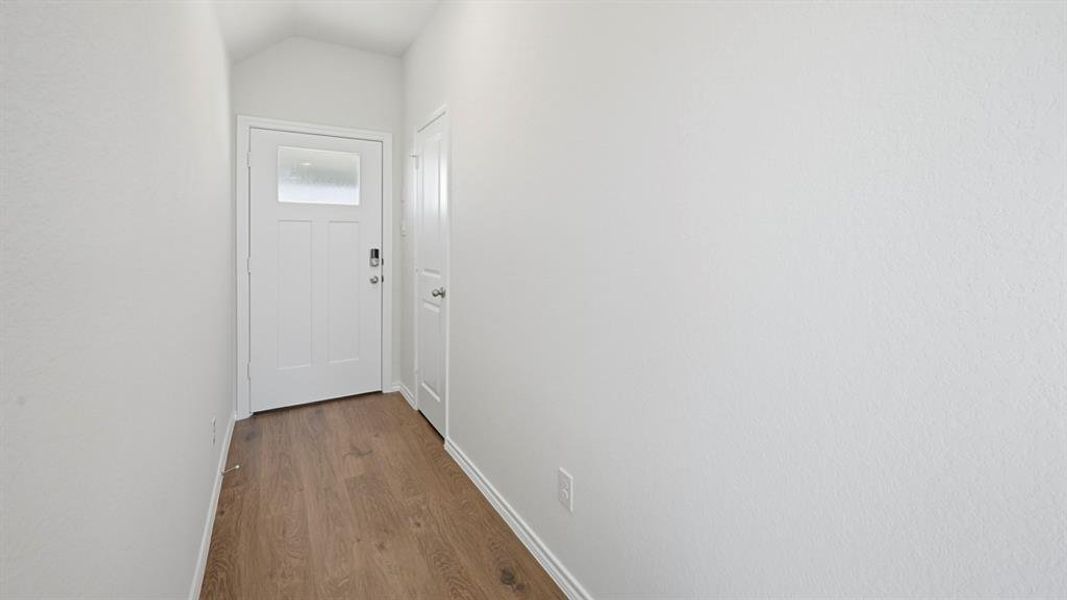 Doorway featuring wood finished floors and vaulted ceiling Doorway featuring wood finished floors and vaulted ceiling