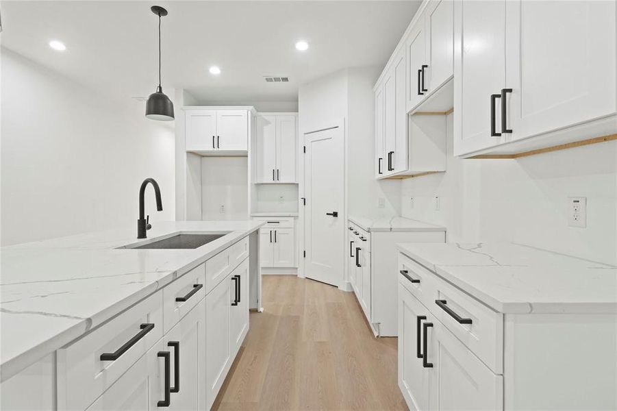 Kitchen featuring light stone countertops, recessed lighting, light wood-style flooring, white cabinetry, and pendant lighting Kitchen featuring light stone countertops, recessed lighting, light wood-style flooring, white cabinetry, and pendant lighting