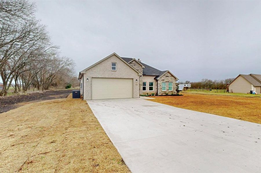 View of front of home with concrete driveway, a front lawn, and stone siding