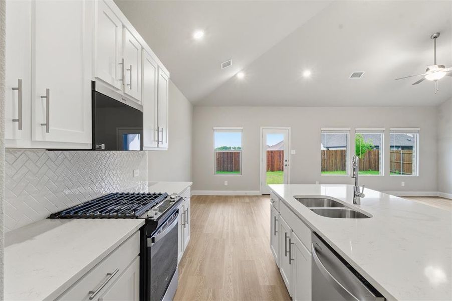 The kitchen features white cabinetry, a gas range with an oven, and a white subway tile backsplash