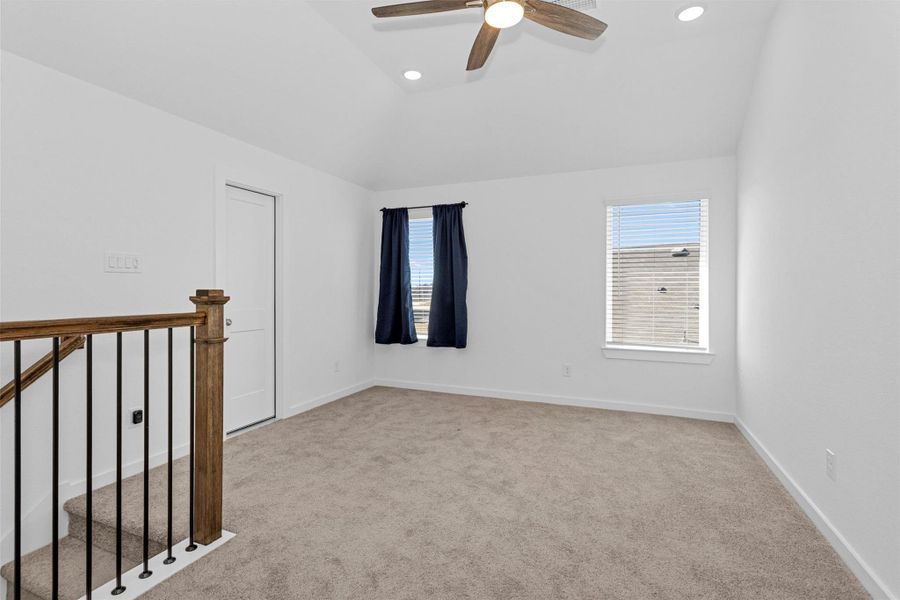 This upstairs game room offers vaulted ceilings, soft carpeting, and plenty of natural light, creating a flexible space for entertainment, a media lounge, or a play area.
