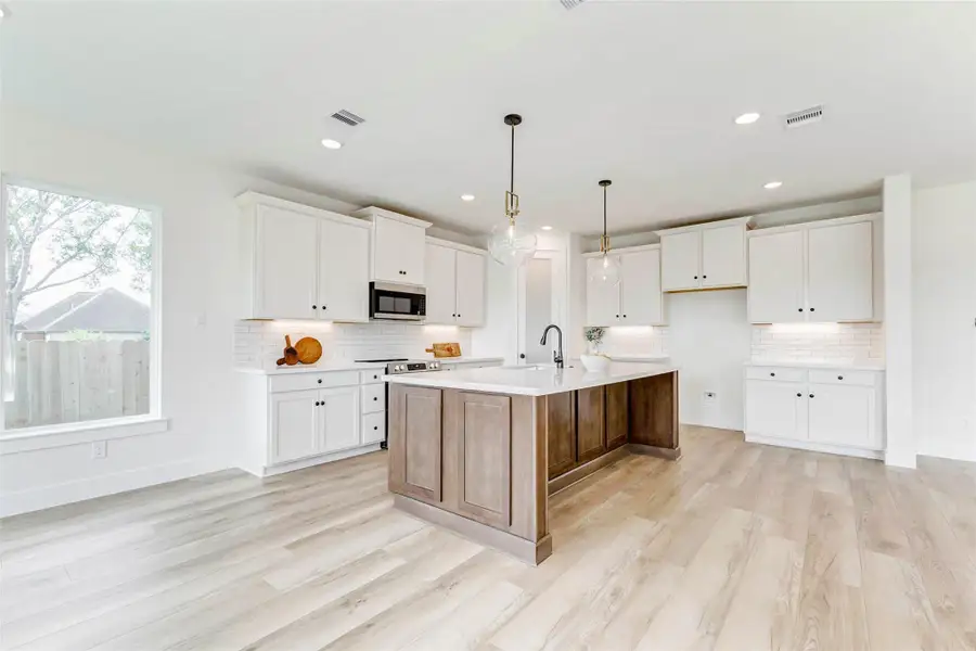 This beautiful island contrasts the rest of the kitchen with it's walnut colored stain and offers at least 4 spaces for countertop stools/chairs.
