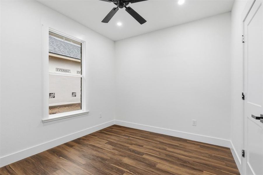 Room featuring wood-finish flooring, a white window frame, white walls, and a ceiling fan with integrated lighting Room featuring wood-finish flooring, a white window frame, white walls, and a ceiling fan with integrated lighting