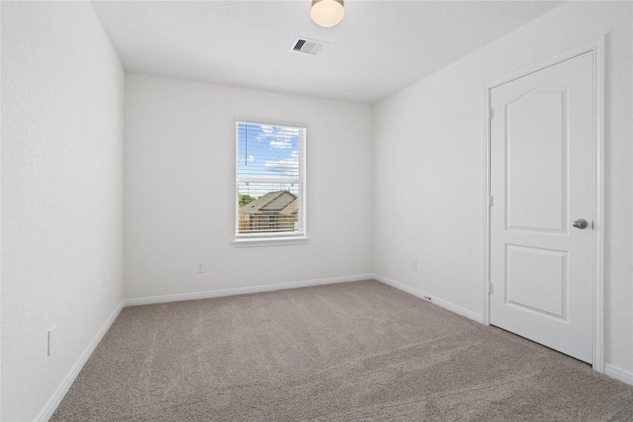 This secondary bedroom offers comfort and style with plush carpeting, neutral paint tones, globe lighting, a large window with blinds, and a walk-in closet. This secondary bedroom offers comfort and style with plush carpeting, neutral paint tones, globe lighting, a large window with blinds, and a walk-in closet.