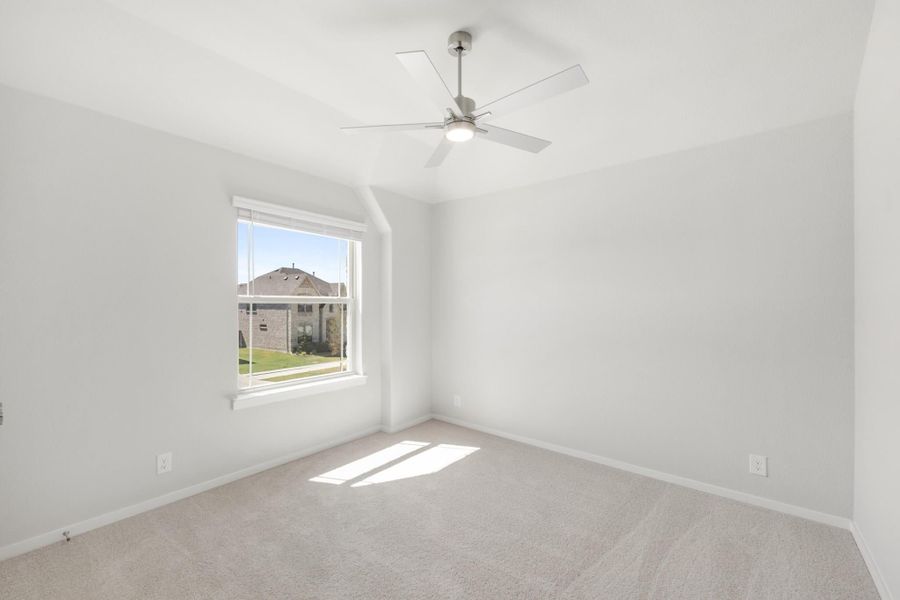 Empty bedroom with vaulted ceiling, ceiling fan, carpet flooring, and a window with natural light Empty bedroom with vaulted ceiling, ceiling fan, carpet flooring, and a window with natural light