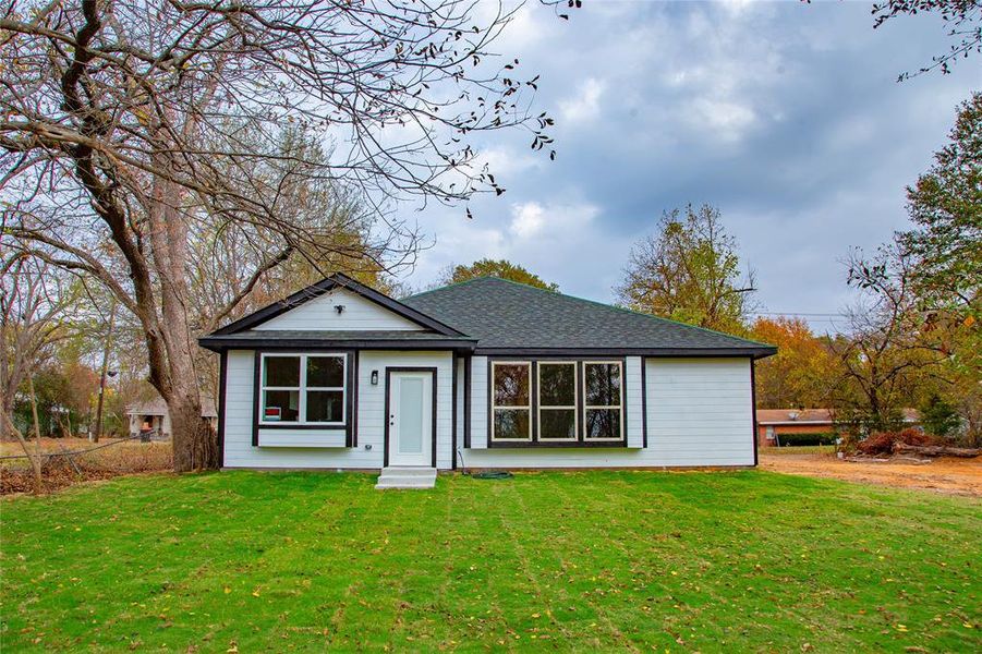 View of front of home featuring a front lawn and a shingled roof