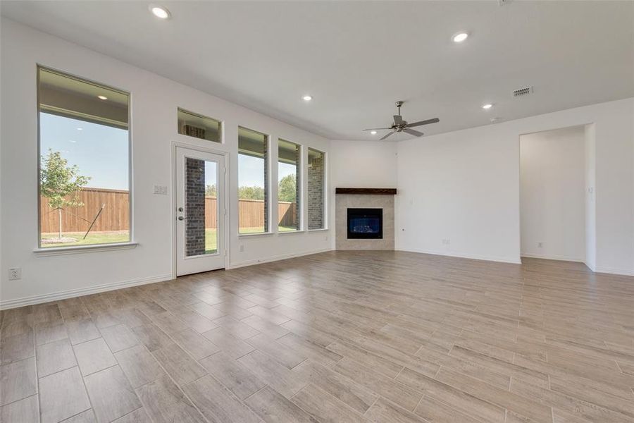 Unfurnished living room featuring ceiling fan, light hardwood / wood-style floors, plenty of natural light, and a tile fireplace