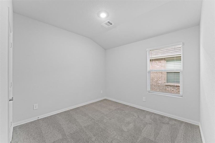 Carpeted spare room with vaulted ceiling and baseboards Carpeted spare room with vaulted ceiling and baseboards