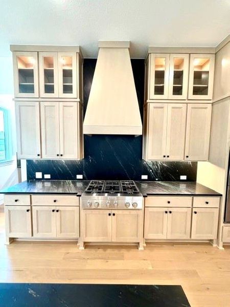 A refined kitchen showcasing a high-performance range with a striking dark backsplash and rich granite countertops. A refined kitchen showcasing a high-performance range with a striking dark backsplash and rich granite countertops.