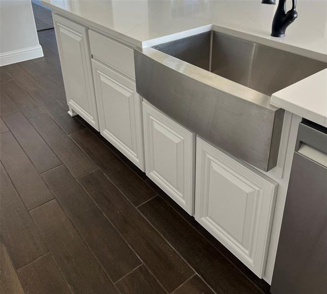 Kitchen view of wood tiled floors, stainless steel dishwasher, and white cabinets