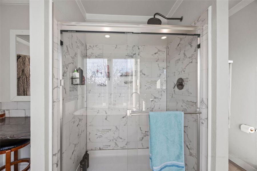 Full bath with a marble finish shower and ornamental molding