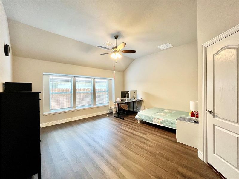 Bedroom with ceiling fan, hardwood / wood-style flooring, and lofted ceiling